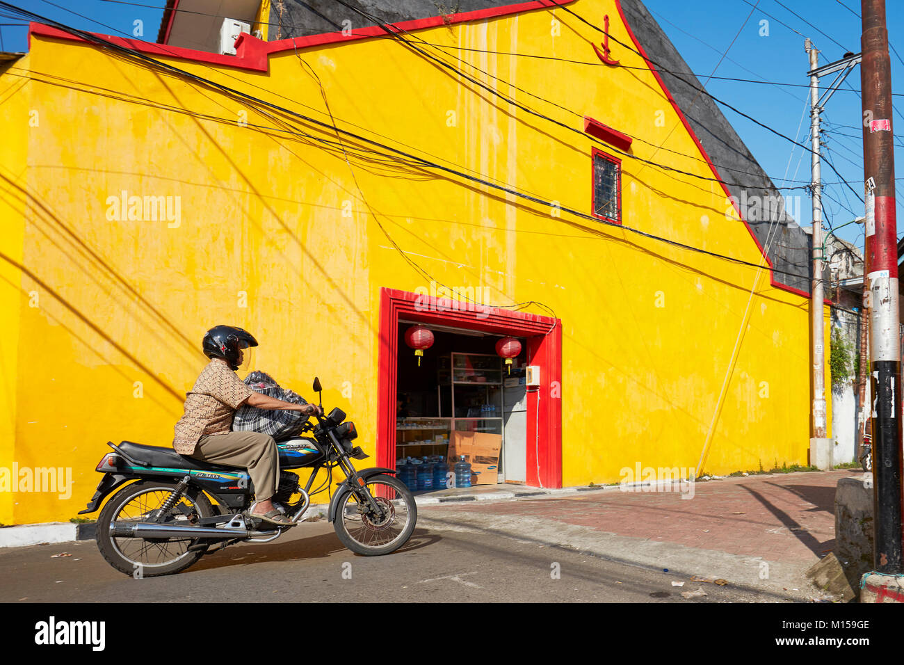 Femme sur moto conduite le long Ketandan Wetan street. Yogyakarta, Java, Indonésie. Banque D'Images