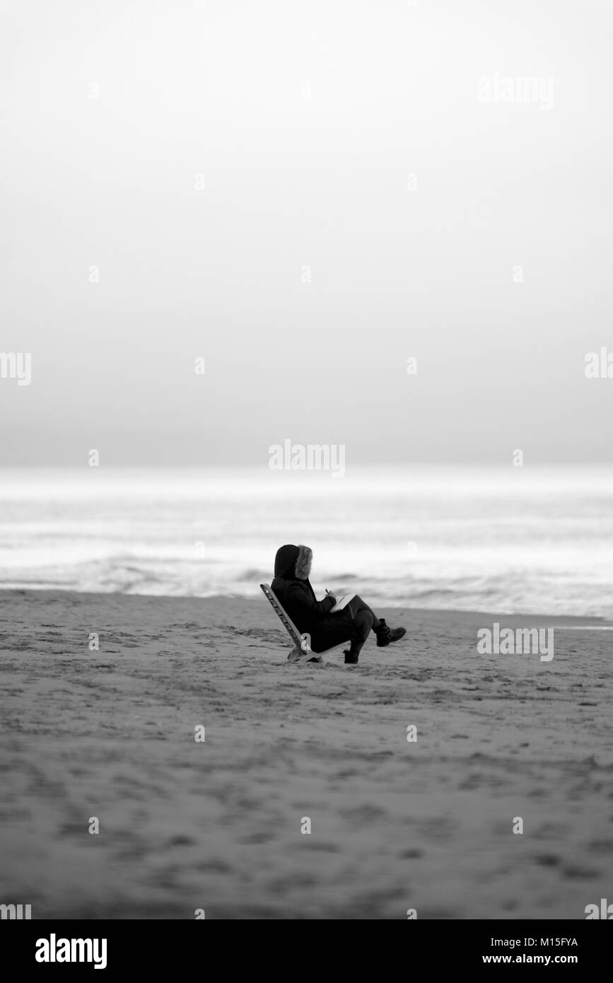 Personne lisant un livre sur la plage d'une mer d'hiver Banque D'Images