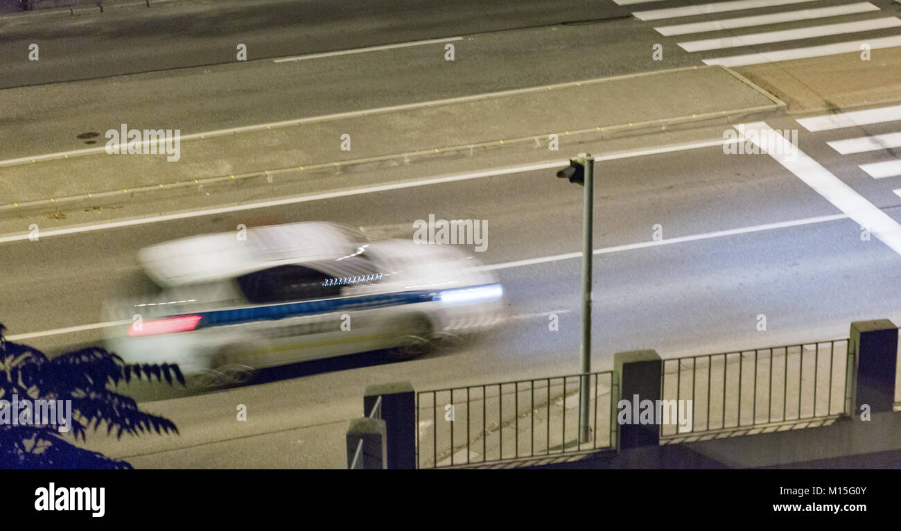 Voiture de police floue se déplace sur city street at night Banque D'Images