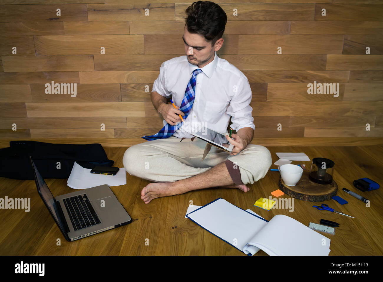 Travail à distance, de penser à une solution. Jeune homme travaillant à domicile dans Drôle de vêtements. Un homme nu est assis sur le plancher Banque D'Images