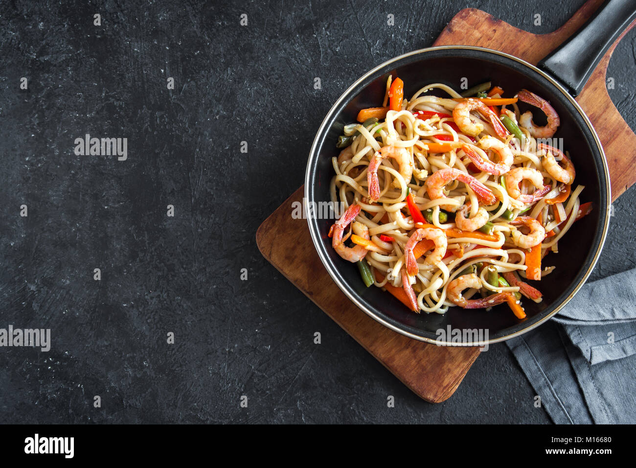 Faire revenir avec les nouilles Udon, crevettes (crevettes) et de légumes. La nourriture saine, de l'Asie, repas sautés au wok sur fond noir, copiez l'espace. Banque D'Images