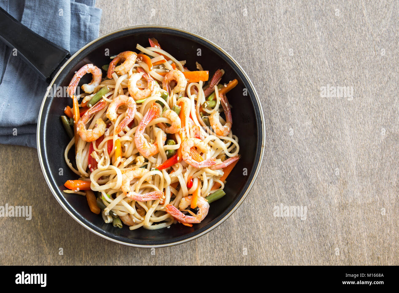 Faire revenir avec les nouilles Udon, crevettes (crevettes) et de légumes. La nourriture saine, de l'Asie, repas sautés au wok sur fond de bois, copie de l'espace. Banque D'Images