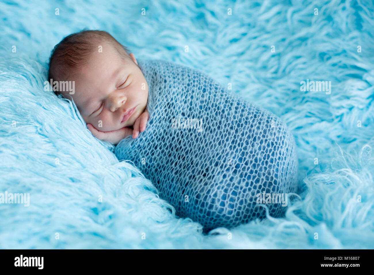 Mignon bébé garçon, dormir paisiblement enveloppée dans un emballage bleu  sur bleu fourrure, de pommes de terre en sac Photo Stock - Alamy