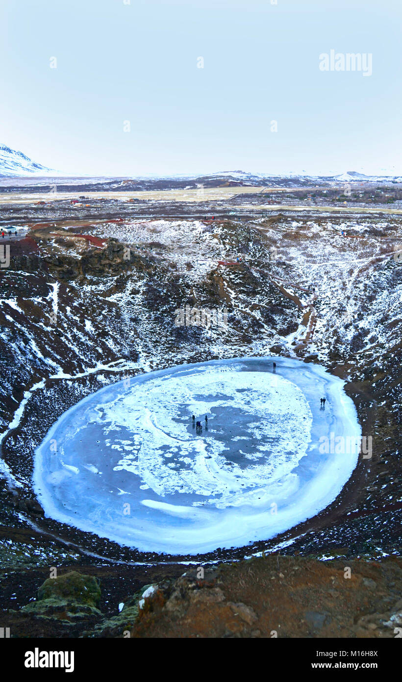 Kerið est un lac de cratère volcanique de Grímsnes dans le sud de l'Islande. C'est un arrêt populaire pour voyager le cercle d'or. On pense que Kerið était à l'origine un volcan qui a éclaté et cône et vidé sa réserve de magma. Une fois que le magma a été appauvri, le poids du cône réduit à une chambre magmatique vide, plus tard pour être rempli d'eau. Le Kerið caldera est composé de roche volcanique rouge et se trouve à environ 55 m de profondeur, 170 m de large et 270 m de diamètre. Il y a peu de végétation dans le cratère à parois abruptes, à l'exception d'un mur avec une pente plus douce qui est couverte de mousse profonde. Kerio - Islande Banque D'Images