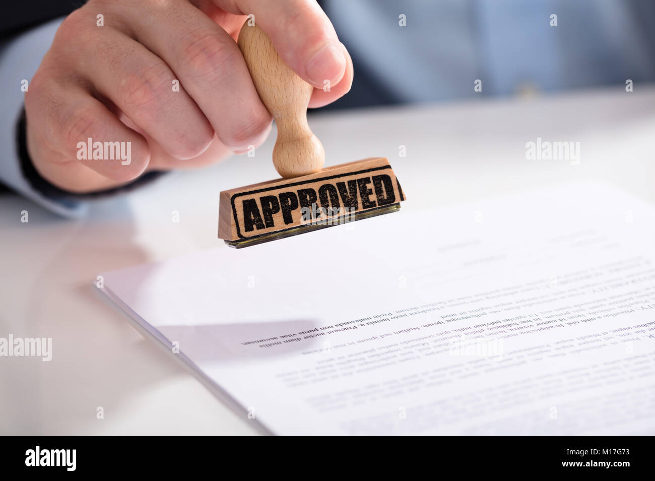 Close-up de l'homme d'affaires à l'aide de la main de Stamper sur Document avec texte approuvé Banque D'Images