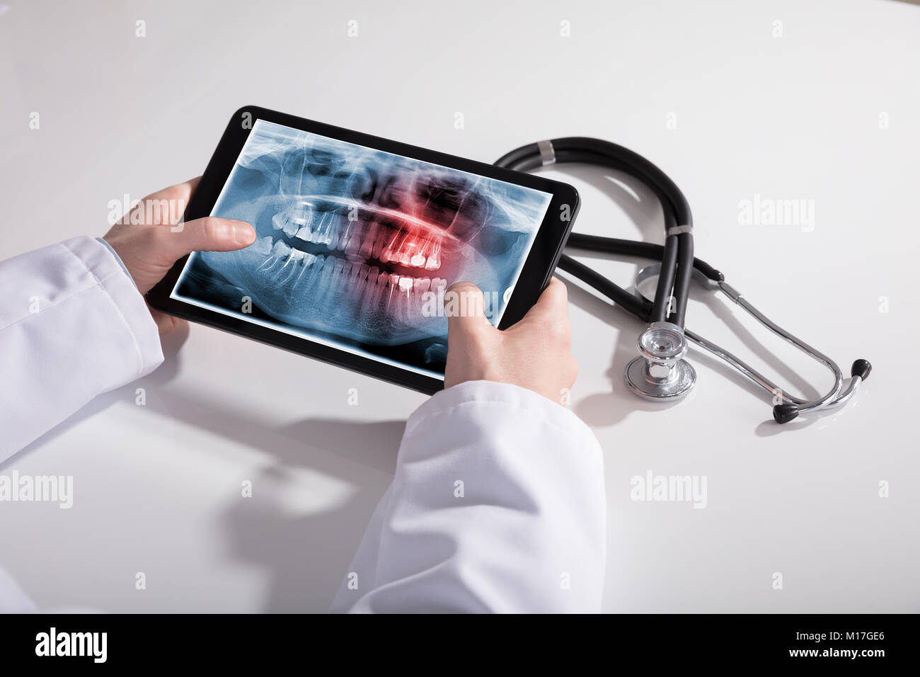Main du médecin et tablette numérique Écran montrant les dents X-ray avec stéthoscope sur blanc 24 Banque D'Images