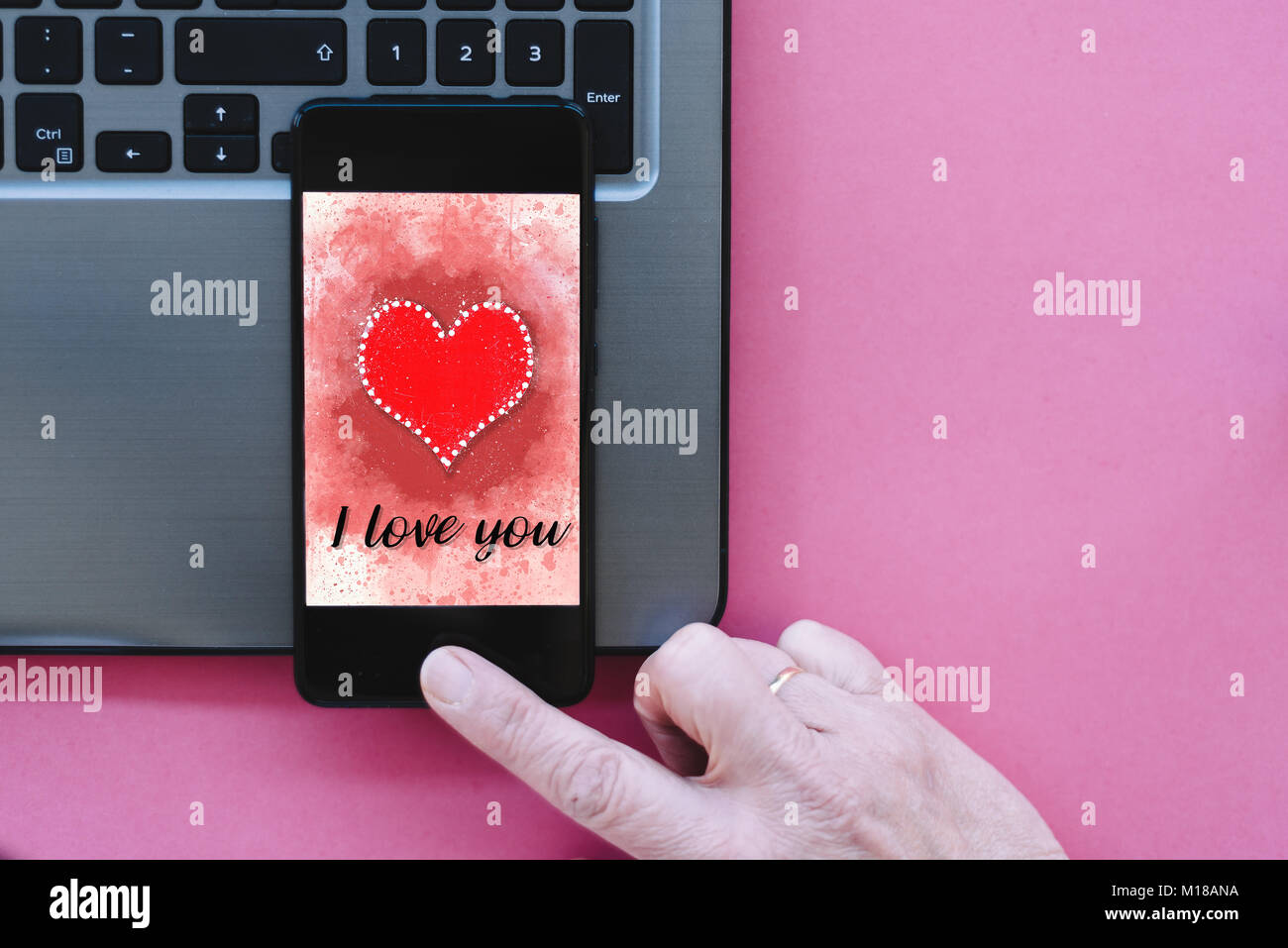 Valentines Day vente fond avec coeur illustration avec les mots je t'aime sur l'écran du smartphone immersive sur fond rose avec un ordinateur portable et d'une femme Banque D'Images