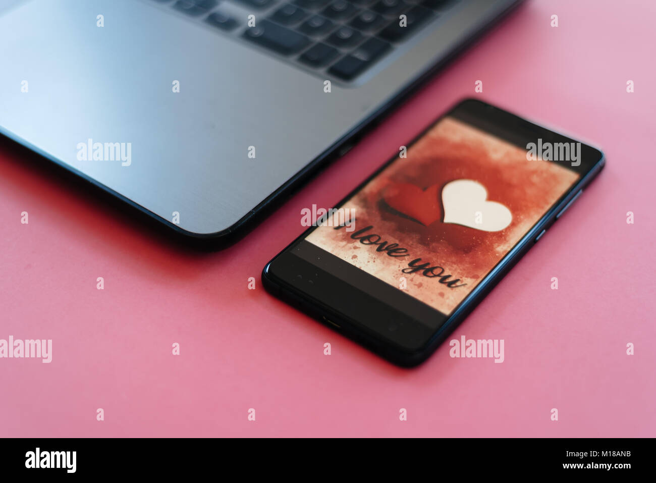 Valentines Day vente fond avec coeur illustration avec les mots je t'aime sur l'écran du smartphone immersive sur fond rose avec portable Banque D'Images