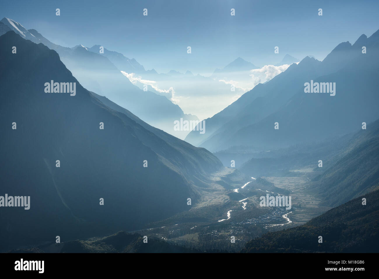 Vue majestueuse de silhouettes de montagnes et nuages bas au coucher du soleil au Népal. Paysage avec de hautes roches de l'himalaya, beau ciel bleu et Banque D'Images