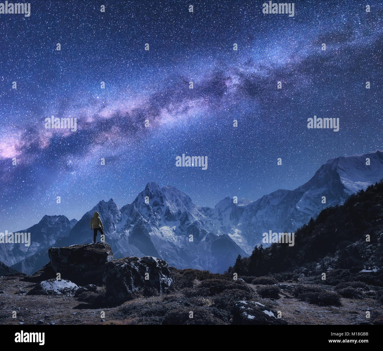 L'espace avec Voie lactée et les montagnes. Homme debout sur la pierre, montagnes et ciel étoilé de nuit au Népal. Roches avec des sommets enneigés contre ciel avec sta Banque D'Images