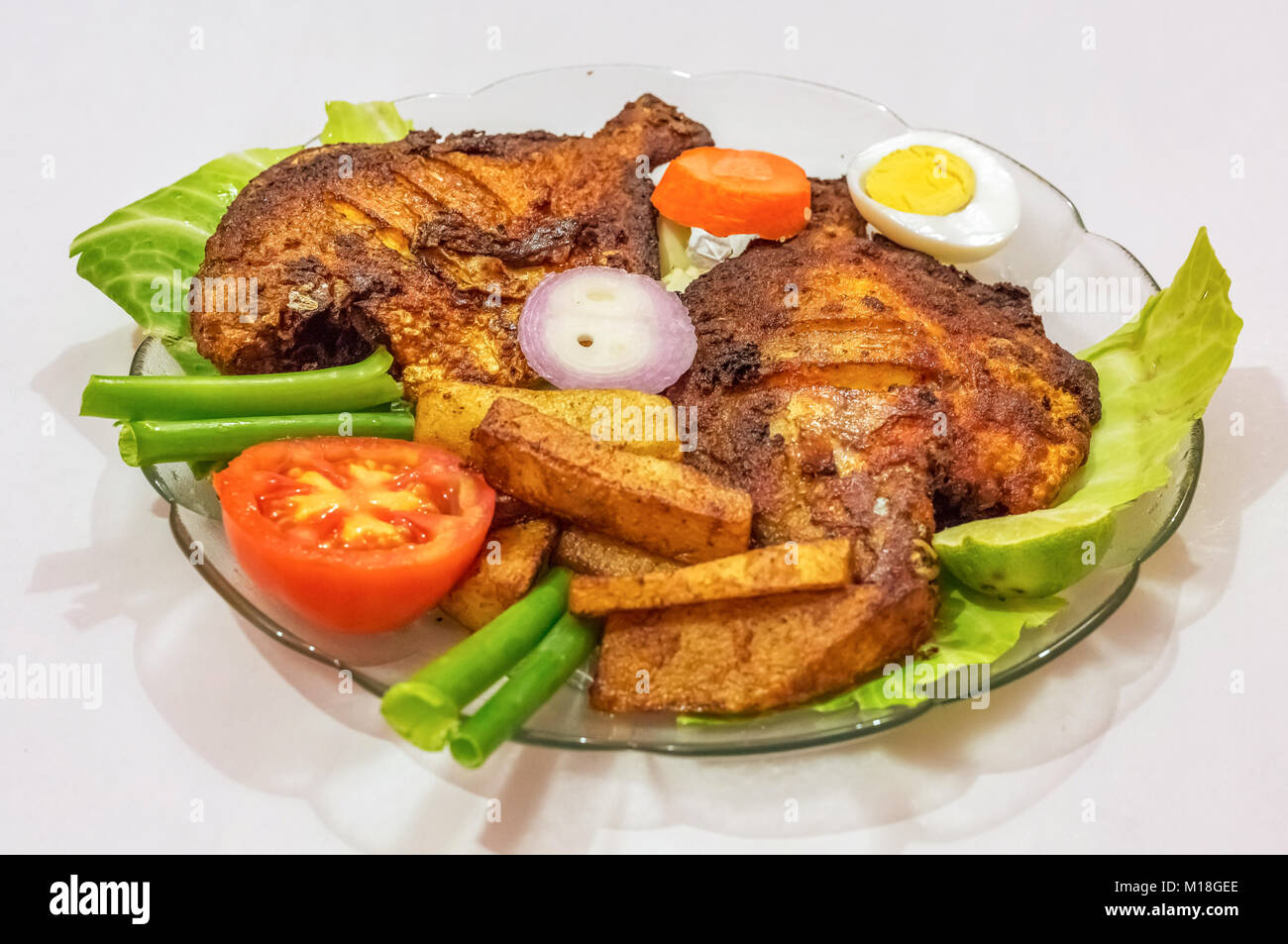 Frit épicé croustillant pomfret poisson avec frites et garni de légumes et les tranches d'oeufs. Une populaire Bengali cuisine indienne. Banque D'Images