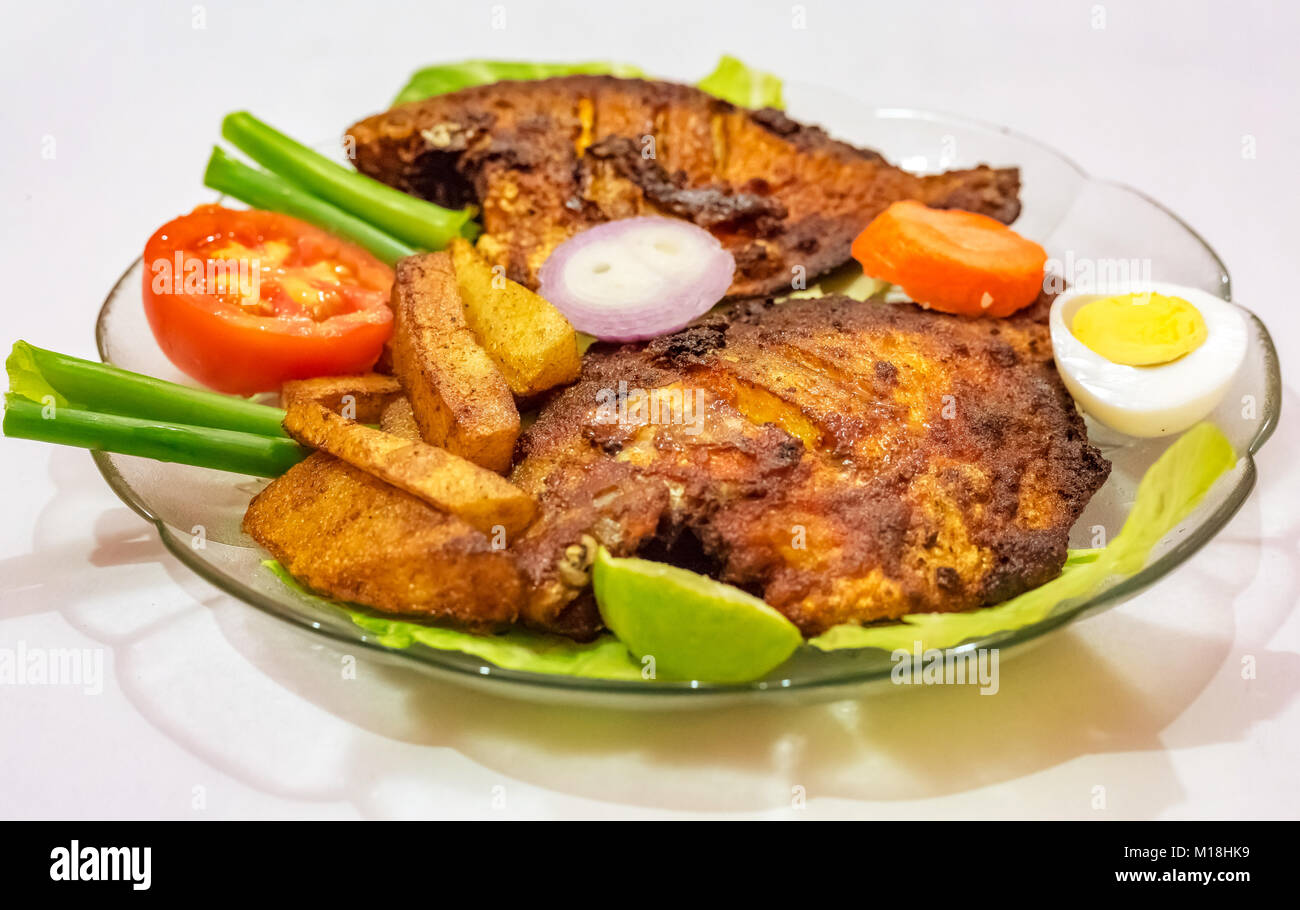 Frit épicé croustillant pomfret poisson avec frites et garni de légumes et les tranches d'oeufs. Une populaire Bengali cuisine indienne. Banque D'Images