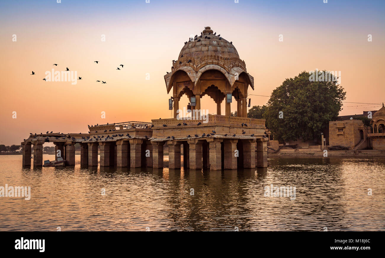 Coucher du soleil à Gadisar Lake (Gadi Sagar) Jaisalmer, Rajasthan avec l'architecture ancienne et de voler les oiseaux. Banque D'Images