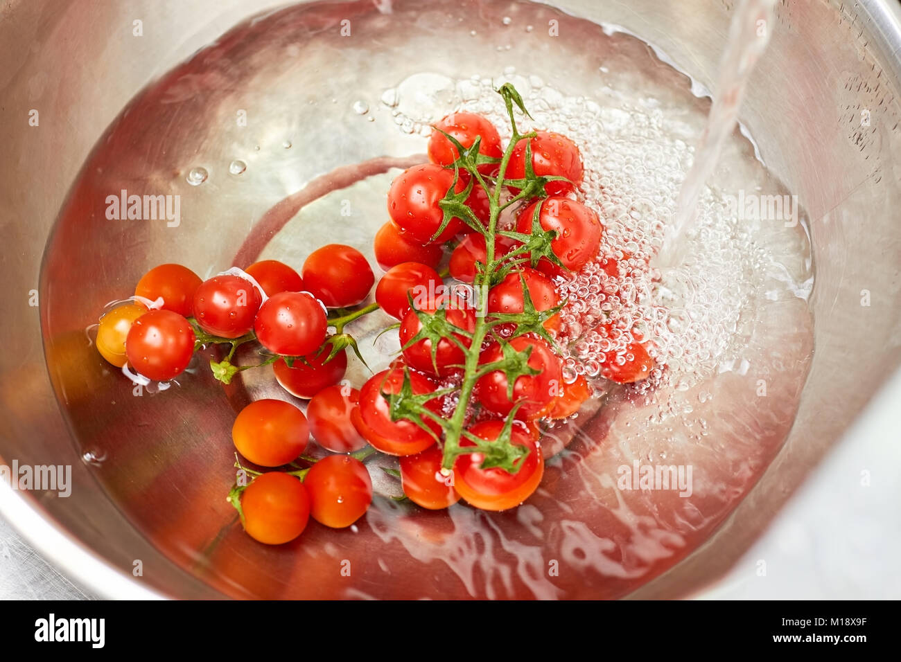Les tomates cerise dans un bol en métal de l'eau, vue d'en haut. Banque D'Images Les tomates cerise dans un bol en métal de l'eau, vue d'en haut. Banque D'Images