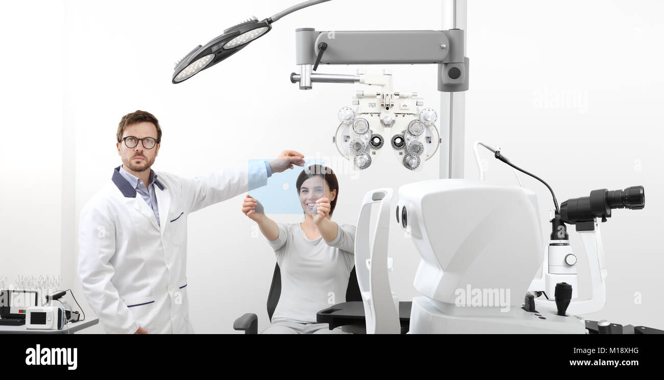 L'examen de la vue patient femme optométriste pointant sur le trou sur plexiglas en bureau de l'opticien, test de dominance oculaire Banque D'Images