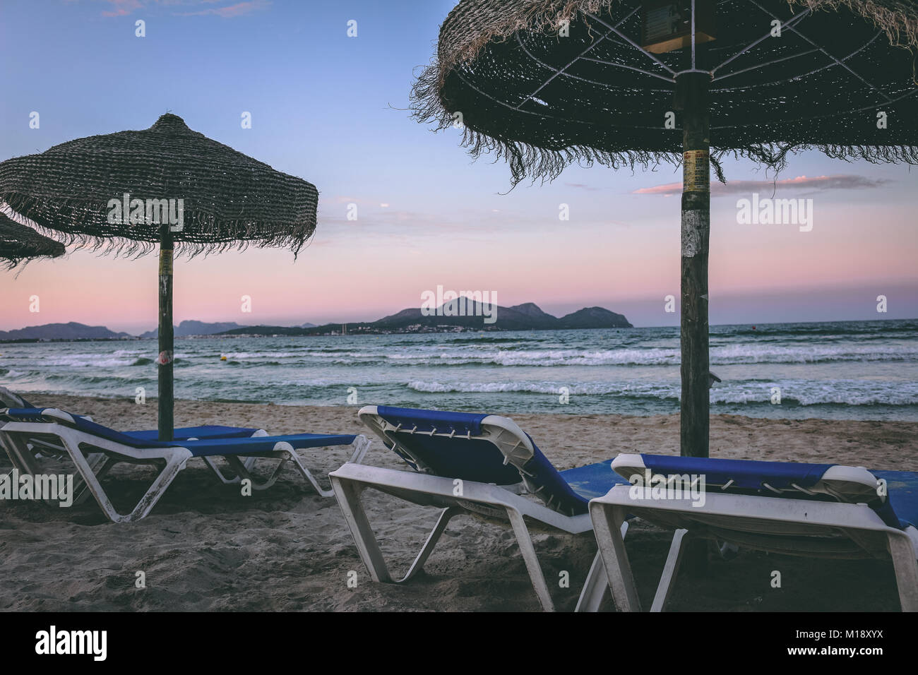Lits de plage et parasols de paille à la plage de Playa de Muro, Alcudia, Mallorca, Espagne belle, à six kilomètres de long Drapeau Bleu, plage de sable blanc. Banque D'Images