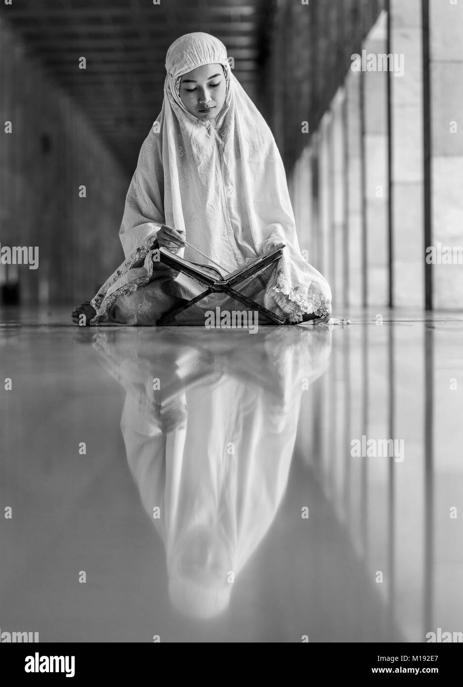 L'Islam girl reading Kuran à l'intérieur de la Mosquée Istiqlal au cours du mois de Ramadan, Jakarta, Indonésie Banque D'Images