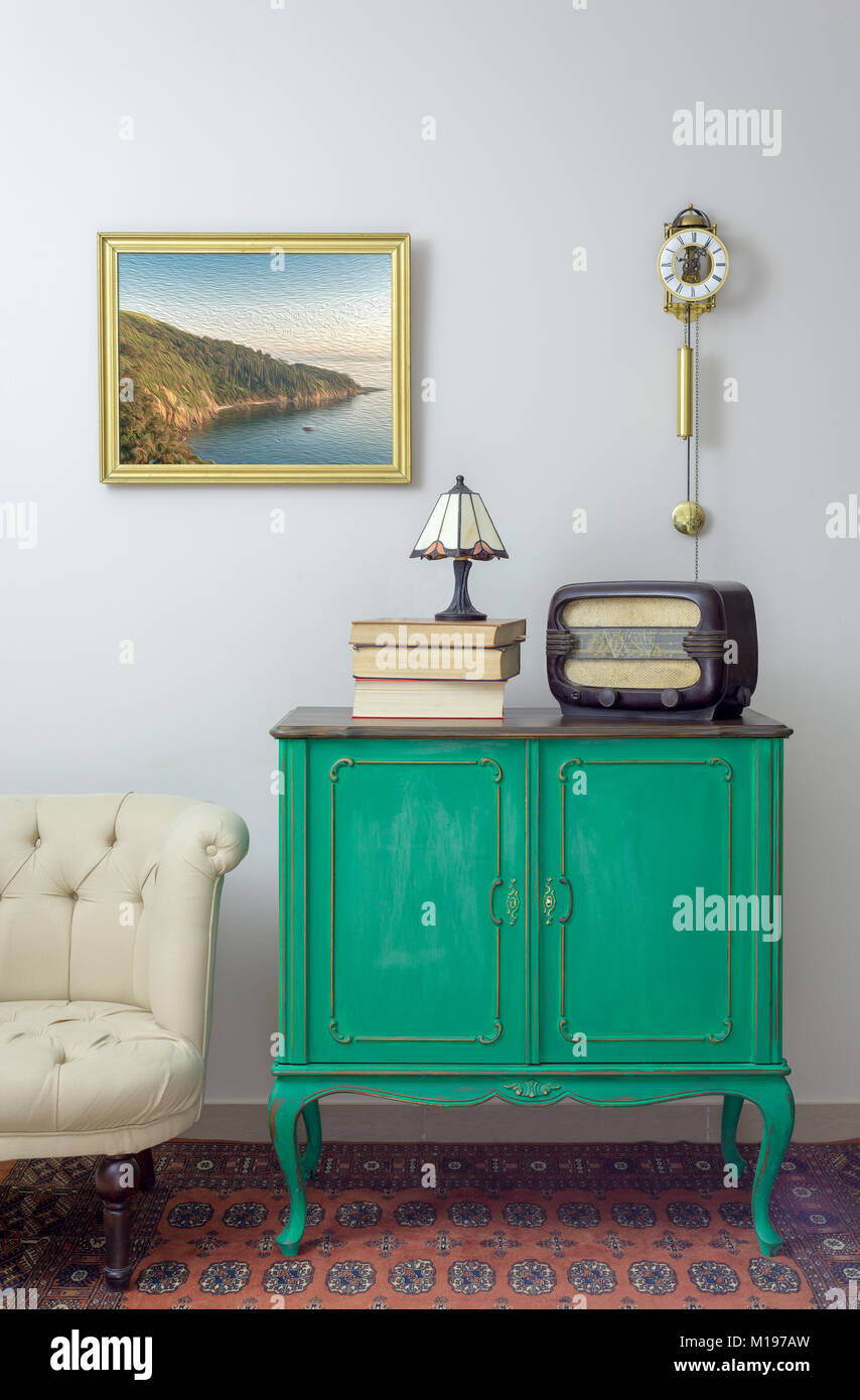 Interior shot of green vintage avec radio ancienne, de vieux livres, et une lampe de table sur fond de mur blanc avec peinture pendu Banque D'Images