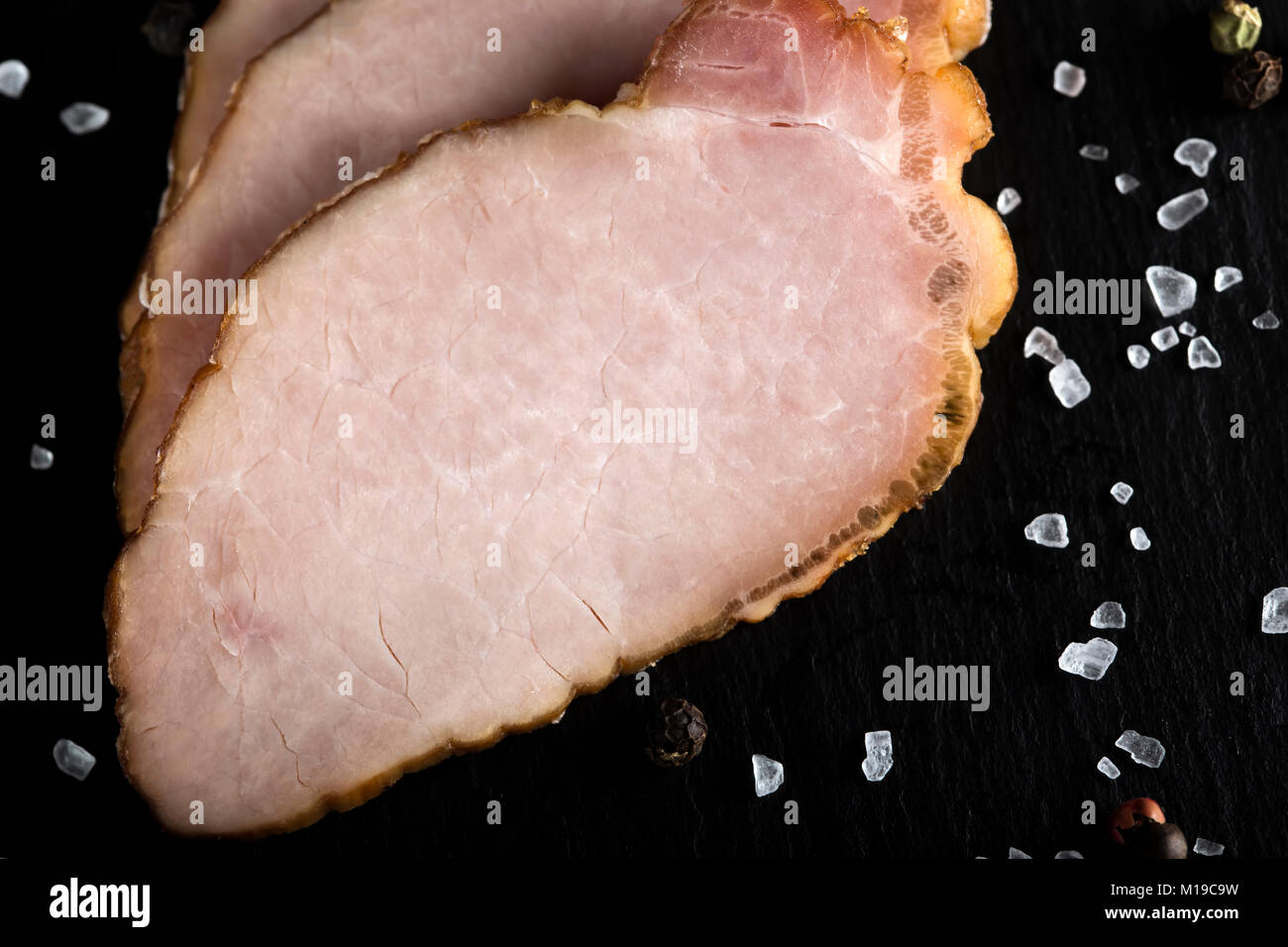 Tranches de porc fumé traditionnel sur ardoise foncé avec du sel et le poivre Banque D'Images