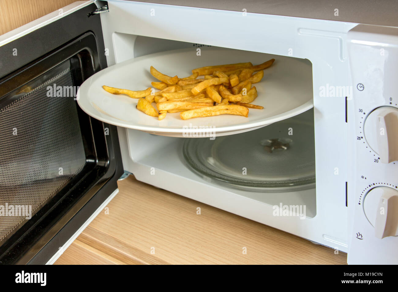 Un four micro-ondes avec une plaque blanche et pommes de terre rôties. Un  grand disque de frites est coincé dans un four micro-ondes Photo Stock -  Alamy