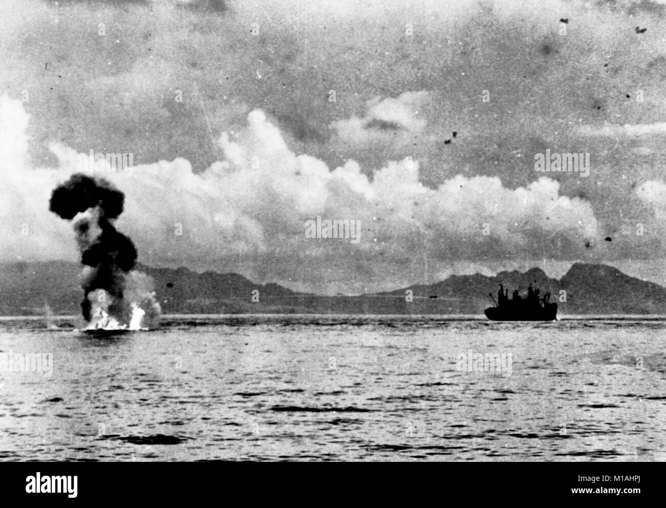 Un Mitsubushi Japonais G4M 'Betty' brûlures d'aéronefs sur l'eau après avoir été abattu par des tirs antiaériens pendant une attaque sur les transports entre Guadalcanal et Tulagi, 7-8 août 1942. Guadalcanal est dans l'arrière-plan, avec les hauteurs au-dessus de Cap Esperance à la droite. Remarque Le G4M en vol au-dessus et à gauche du transport. Banque D'Images