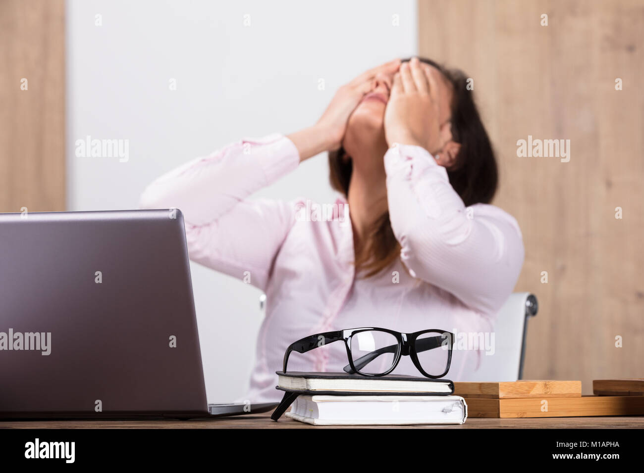 Two Businesswomen avec un journal sur des lunettes sur Desk In Office Banque D'Images