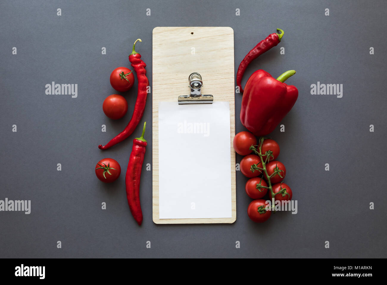 Vue de dessus de poivrons et tomates rouges mûres avec feuille de papier blanc sur gris Banque D'Images