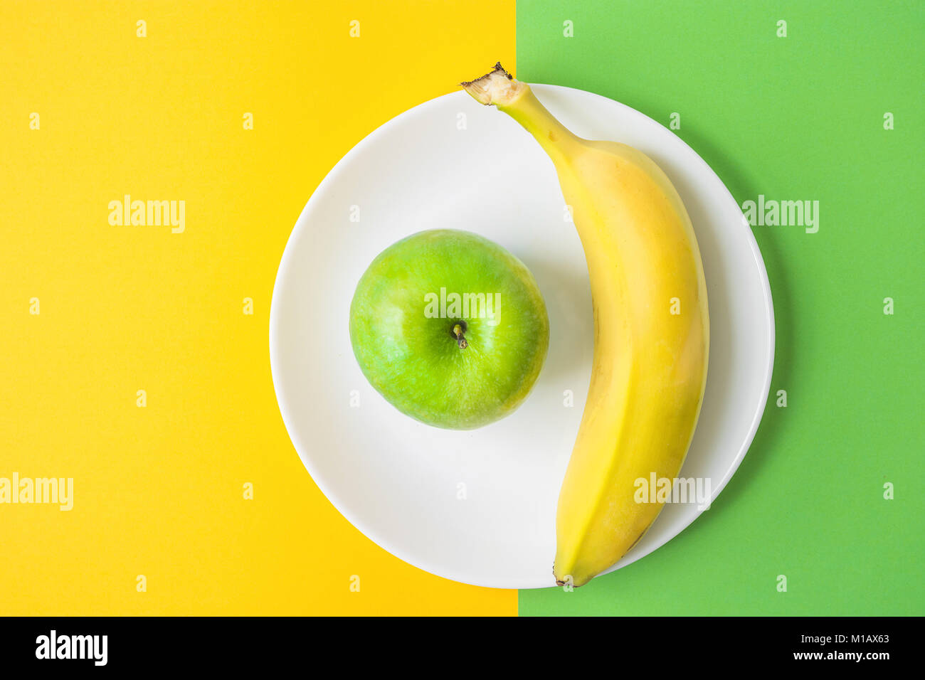 Green Apple Banana sur plaque blanche sur fond de contraste à partir de la combinaison de couleurs jaune et vert. Vitamines Régime Sain Detox Printemps Été Vegan. Banque D'Images