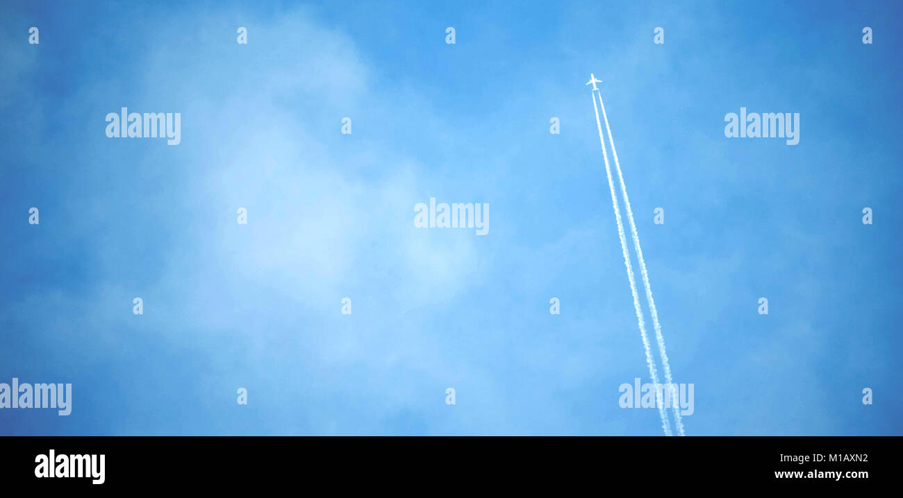 L'avion blanc volant dans le ciel et de laisser les pistes dans les nuages. Banque D'Images