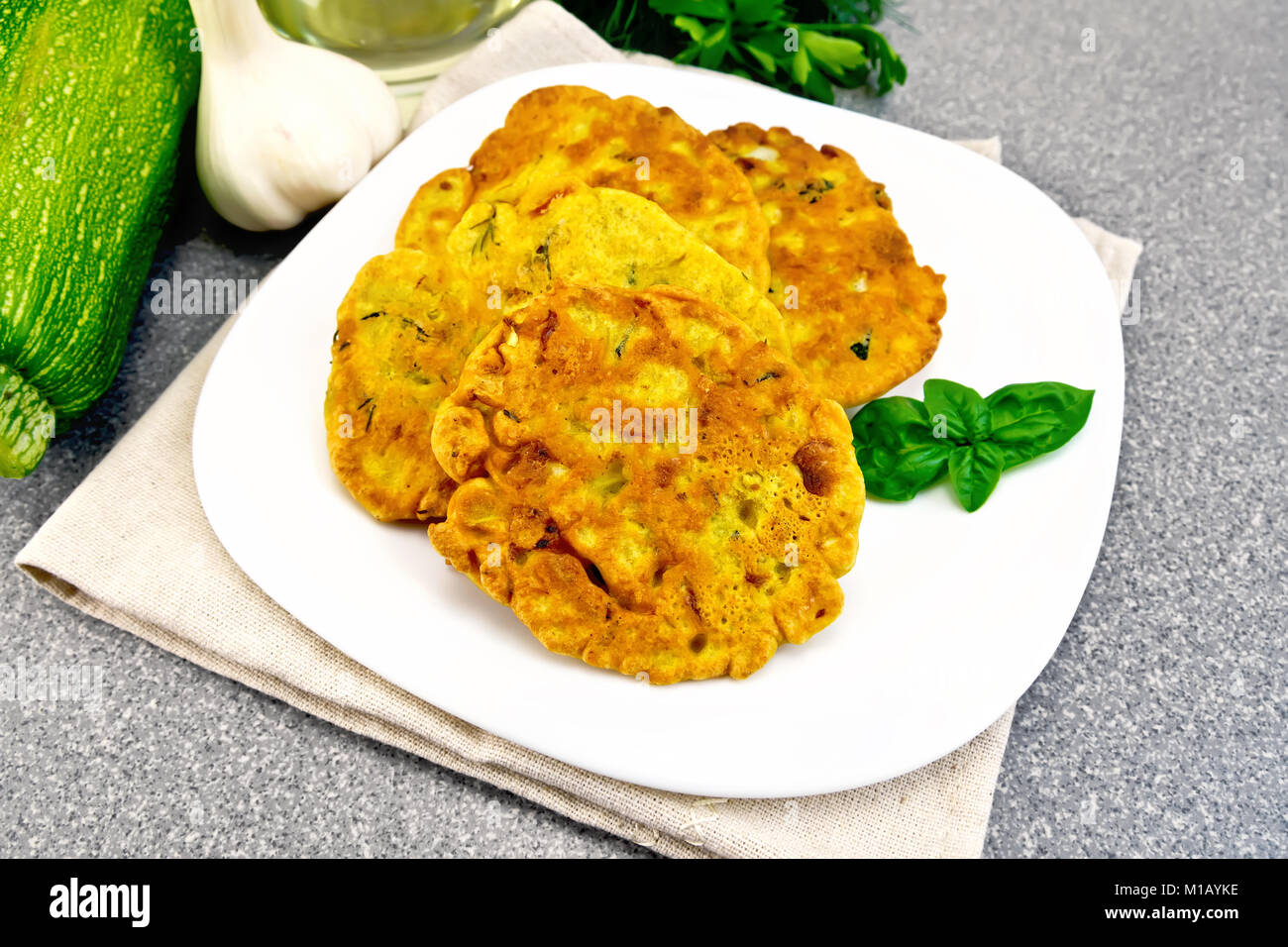 La farine de pois chiches indienne avec pain plats courgettes et herbes fraîches, basilic dans une assiette sur une serviette, l'ail et l'huile dans la carafe sur l'arrière-plan de la Banque D'Images