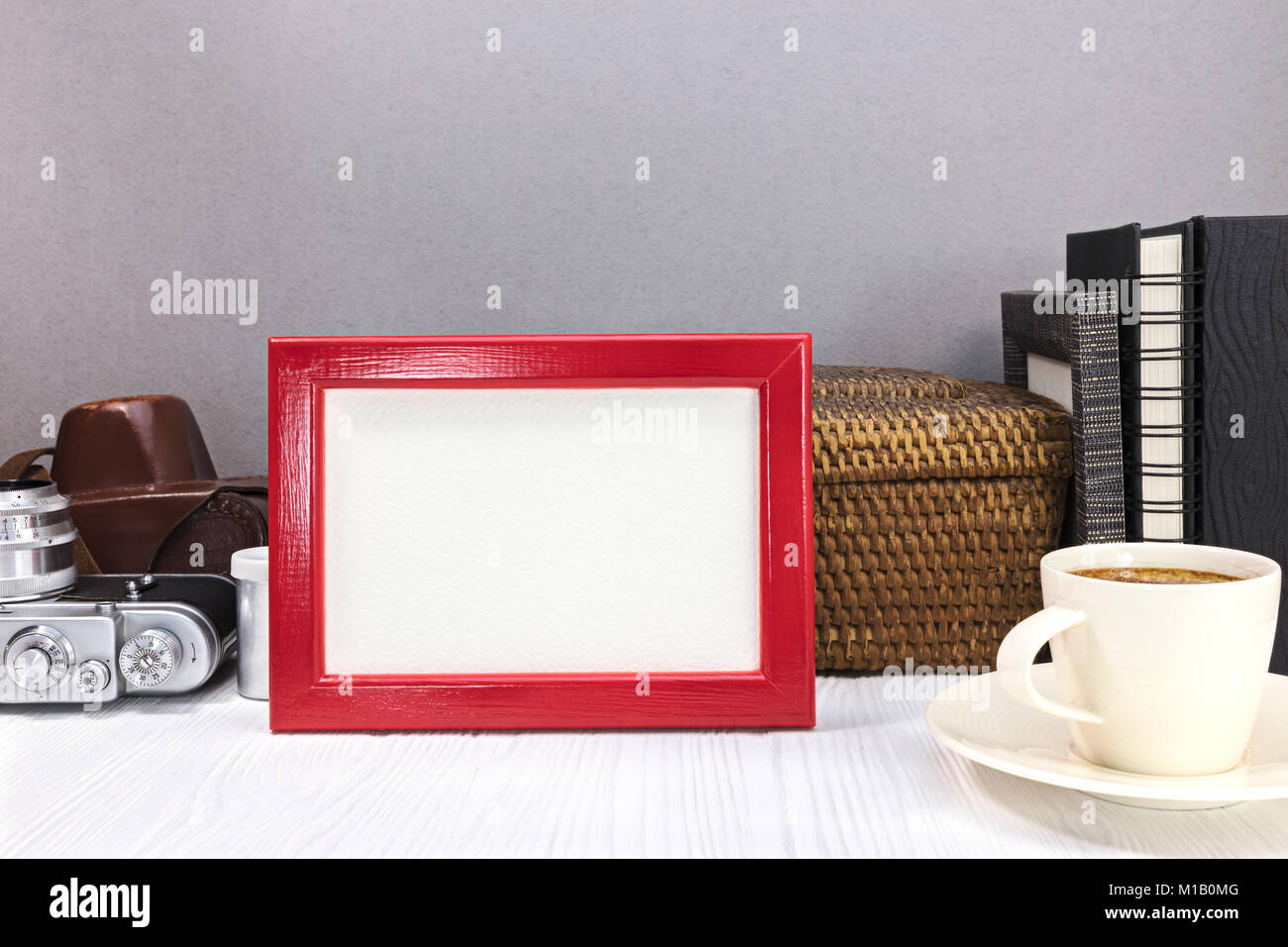 Cadre photo rouge, ancien appareil photo avec couverture en cuir, d'albums photos et de tasse de café sur le bureau. vieux souvenirs concept. Banque D'Images