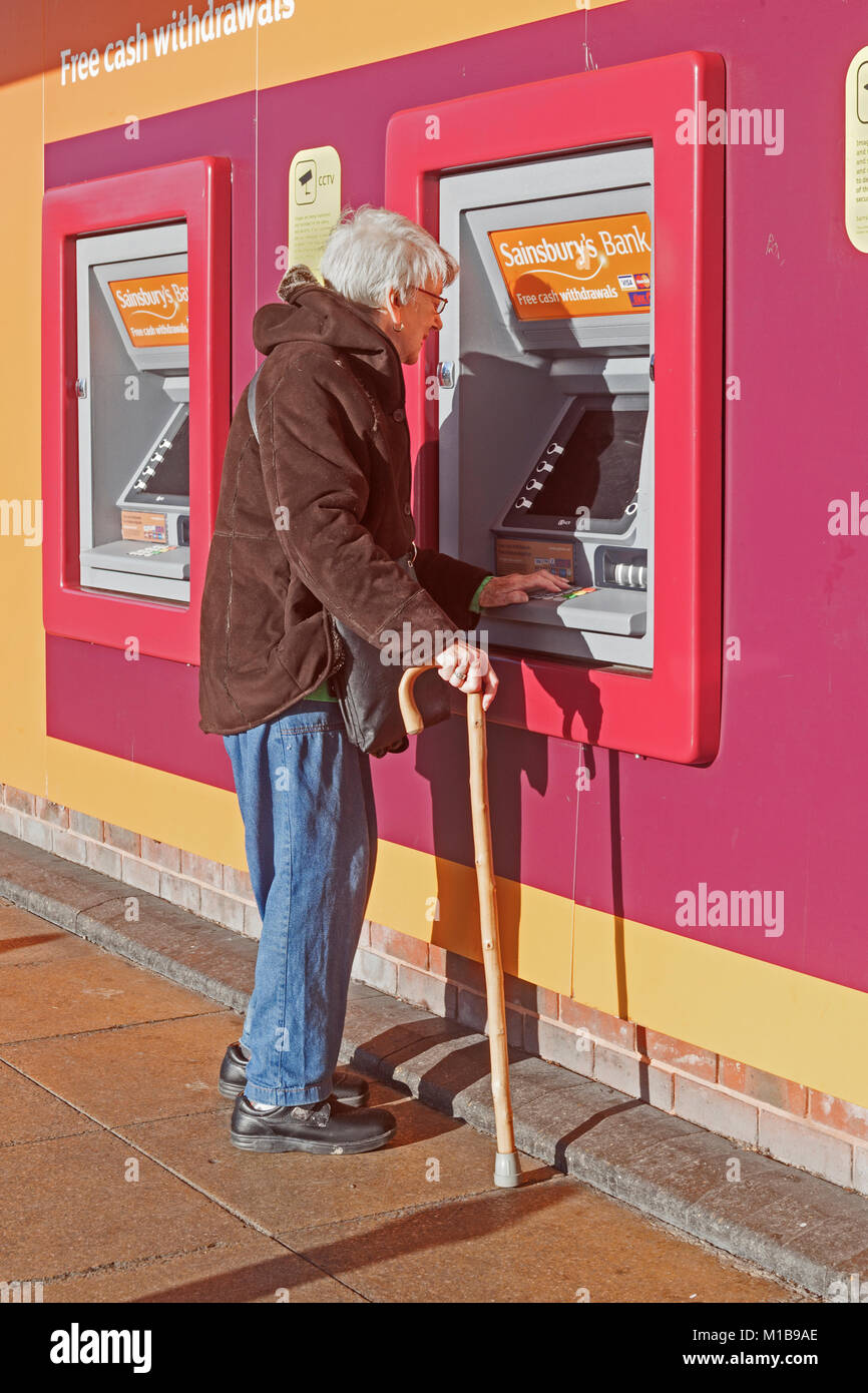Un vieux client travaillant sur la complexité d'un distributeur automatique de billets Banque D'Images
