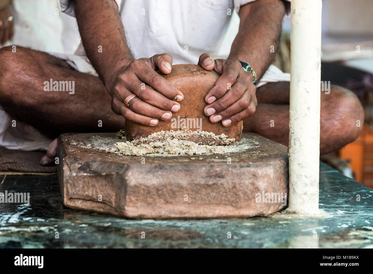 Thandai vendeur préparer / thandai meulage masala fait du cardamome, safran, amandes, graines de fenouil avec les mains sur base de bois à Nathdwara, Rajasthan, JE Banque D'Images