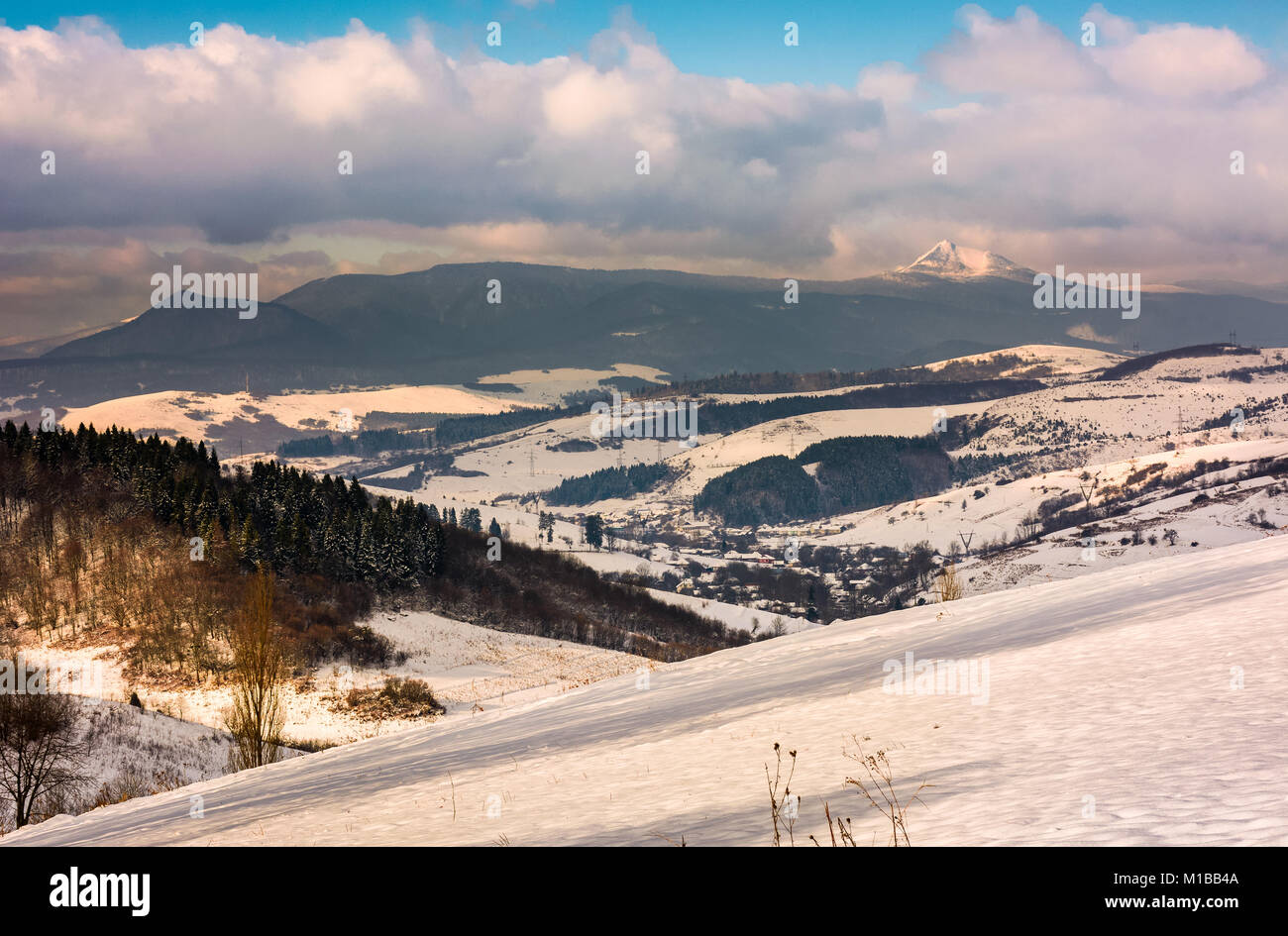 Pente enneigée en campagne montagneuse. superbe météo avec nuages sur la crête de montagne. Banque D'Images