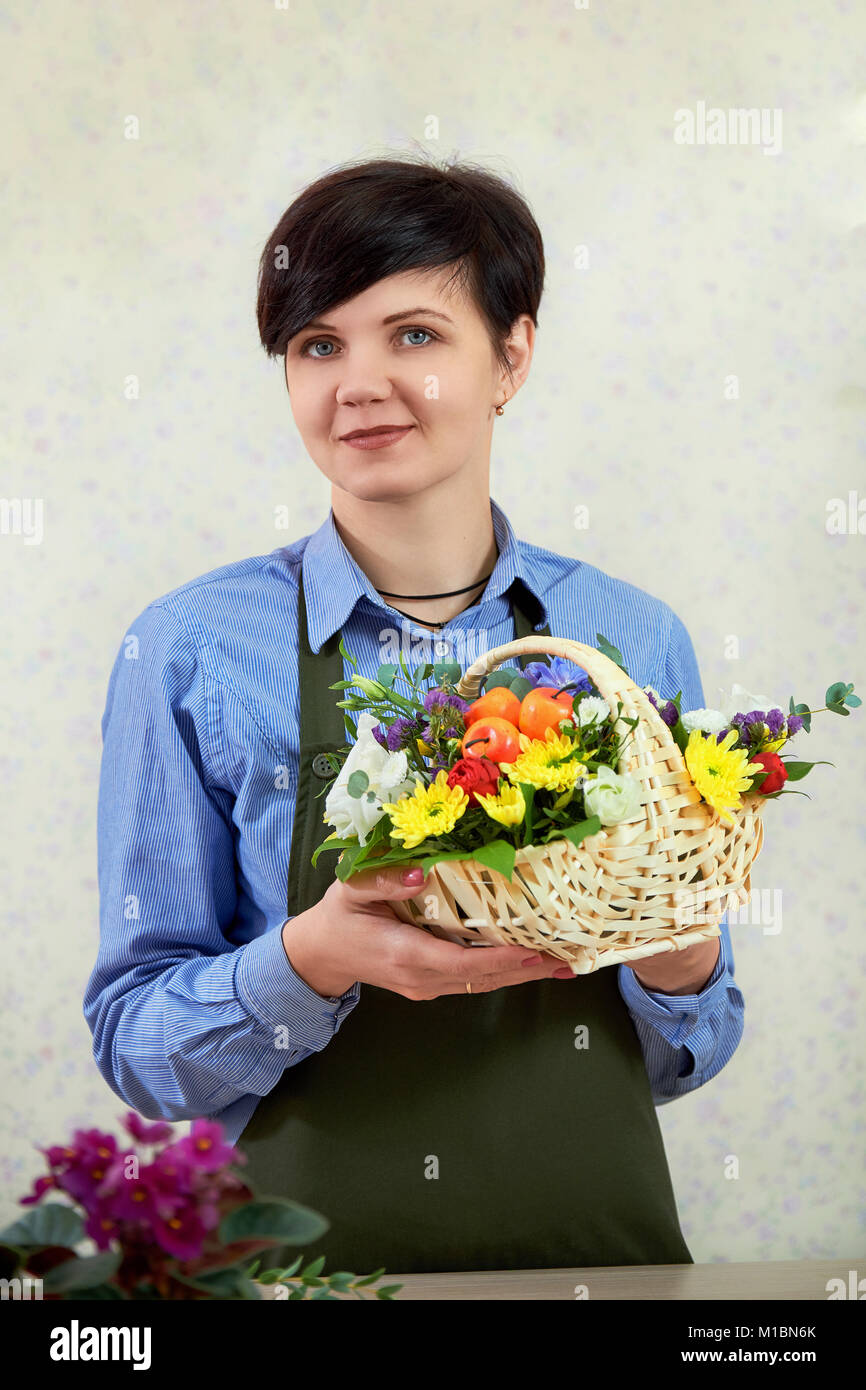 Jeune femme travaillant dans le magasin de fleurs fleuriste. Un vendeur fleuriste femme est titulaire d'une composition de fleurs. Banque D'Images
