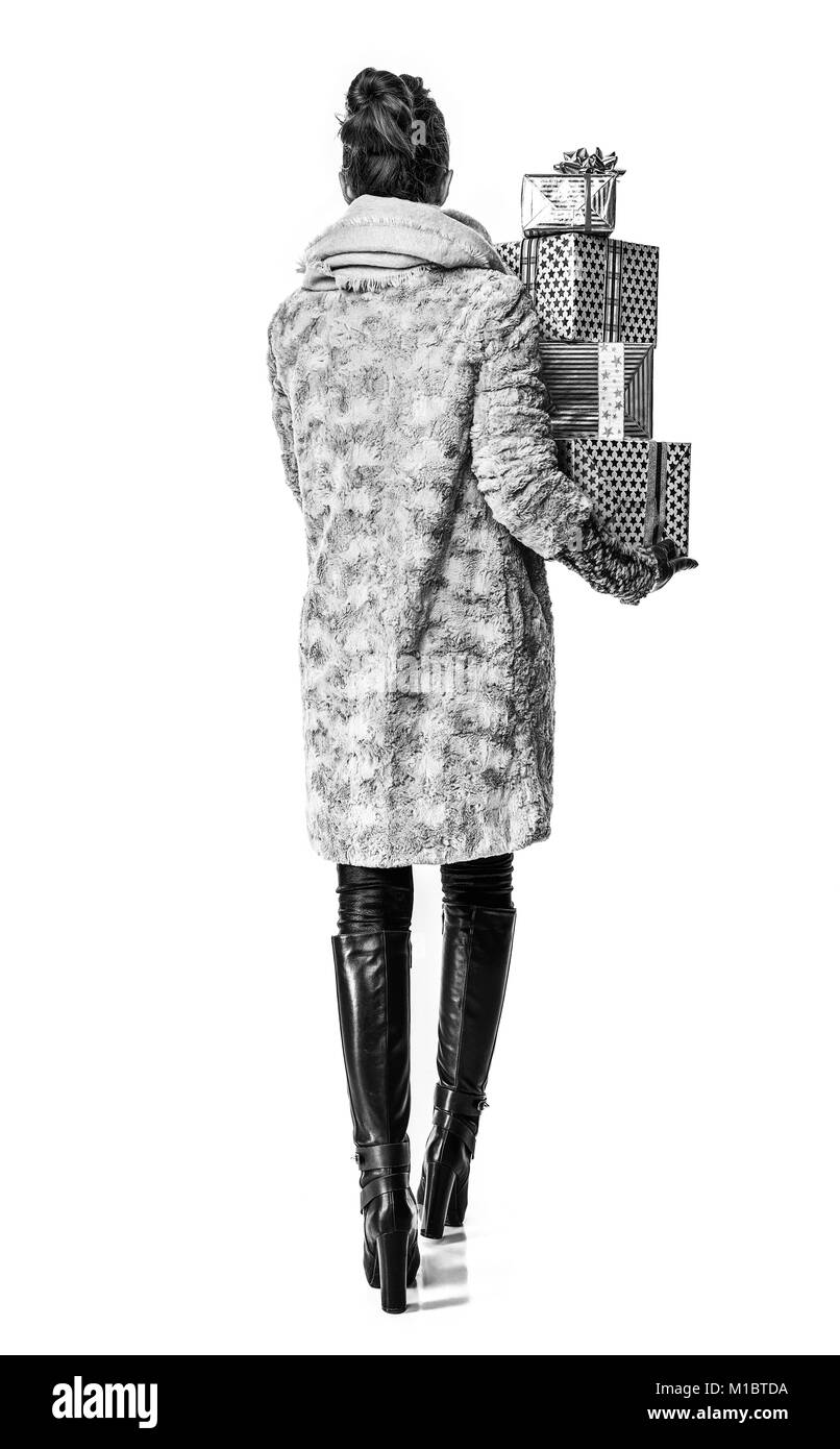 Choses d'hiver. Vus de derrière, la mode chic-monger en manteau d'hiver isolé sur blanc avec des tas de boîtes cadeau de Noël balade Banque D'Images
