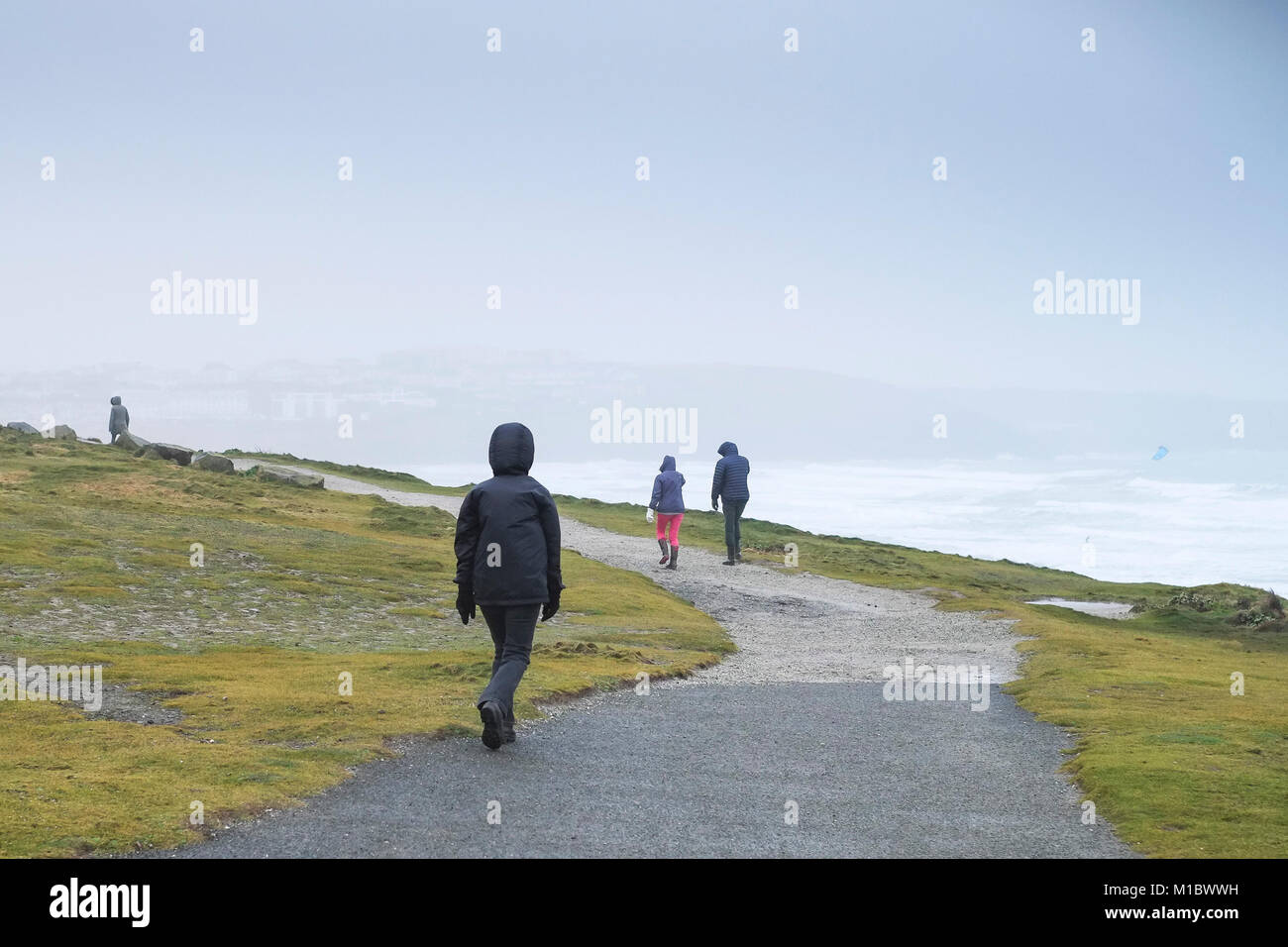 UK de l'hiver - les gens promeneurs marchant sur le South West Coast Path lors de conditions météorologiques hivernales froides Newquay Cornwall. Banque D'Images