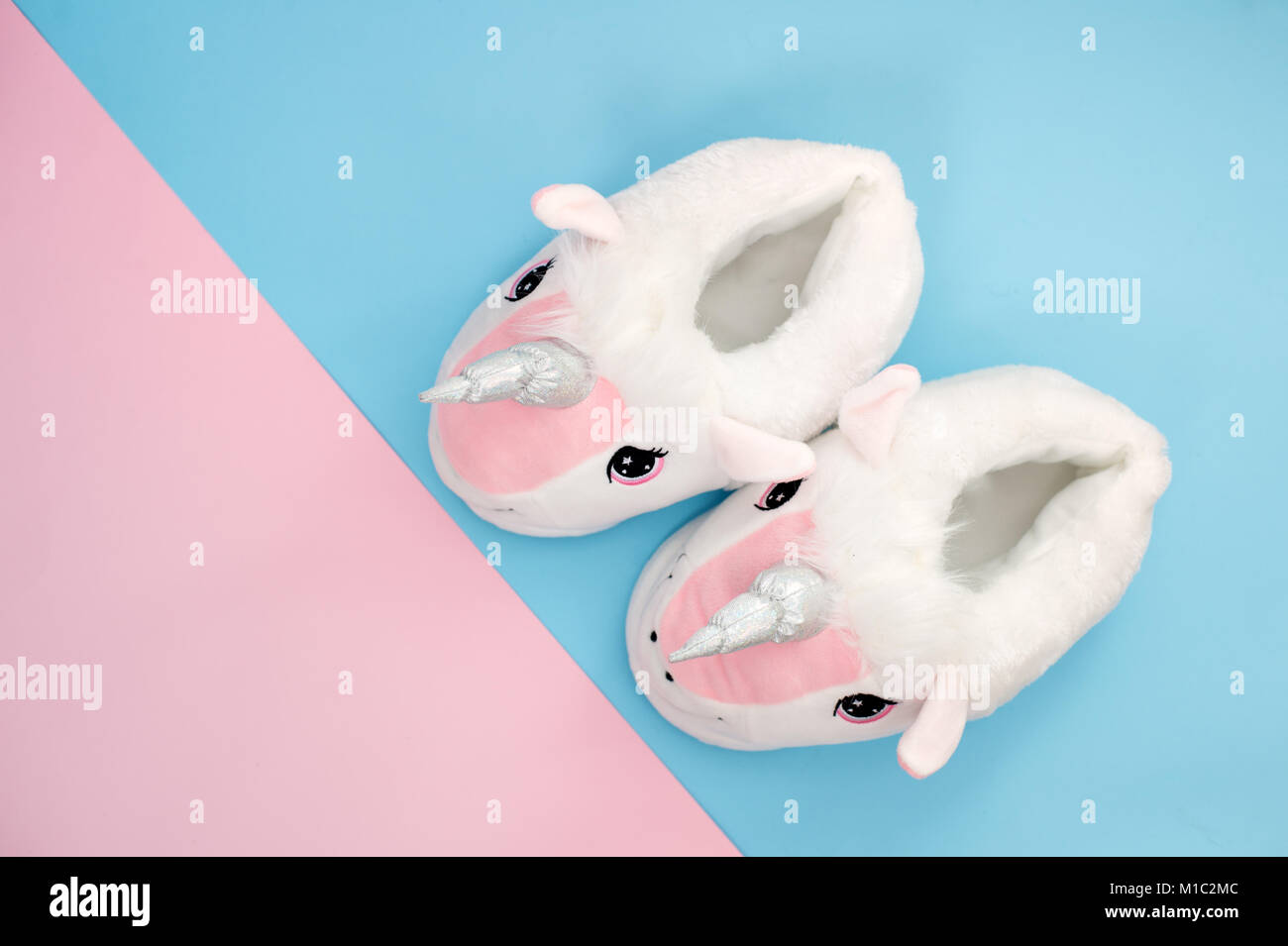 Paire de chaussons moelleux licorne rose sur fond bleu style pop art Banque D'Images