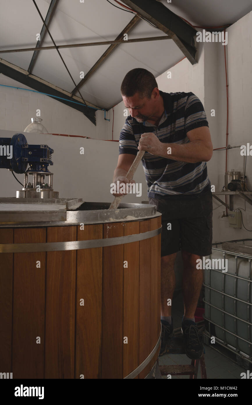 Travailleur homme remuant dans gin distillery Banque D'Images