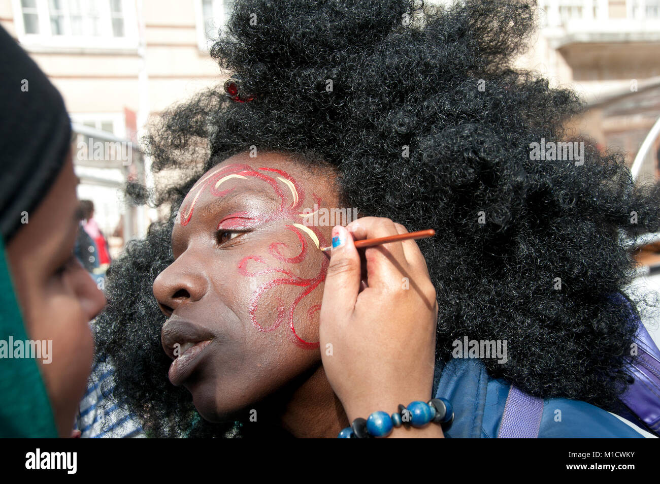 La Journée internationale de la femme le 8 mars 2009. Une femme portant un voile peint le visage d'une femme afro-antillaise Banque D'Images