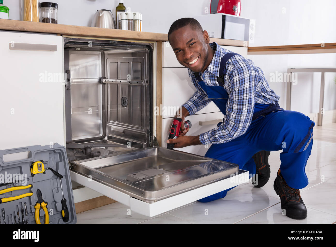 De jeunes Africains dans la cuisine lave-vaisselle fixation réparateur Banque D'Images