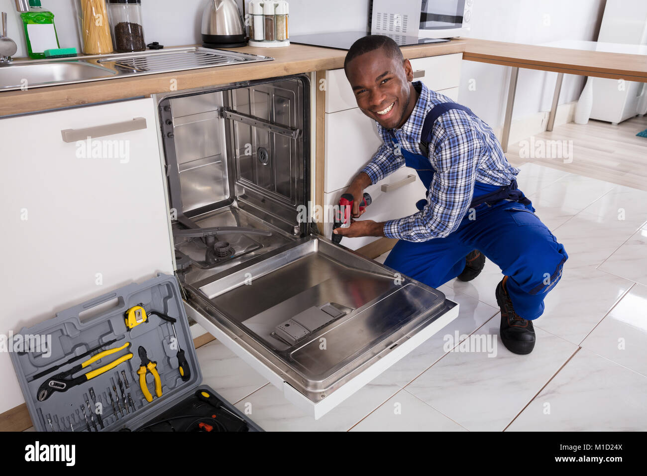 De jeunes Africains dans la cuisine lave-vaisselle fixation réparateur Banque D'Images