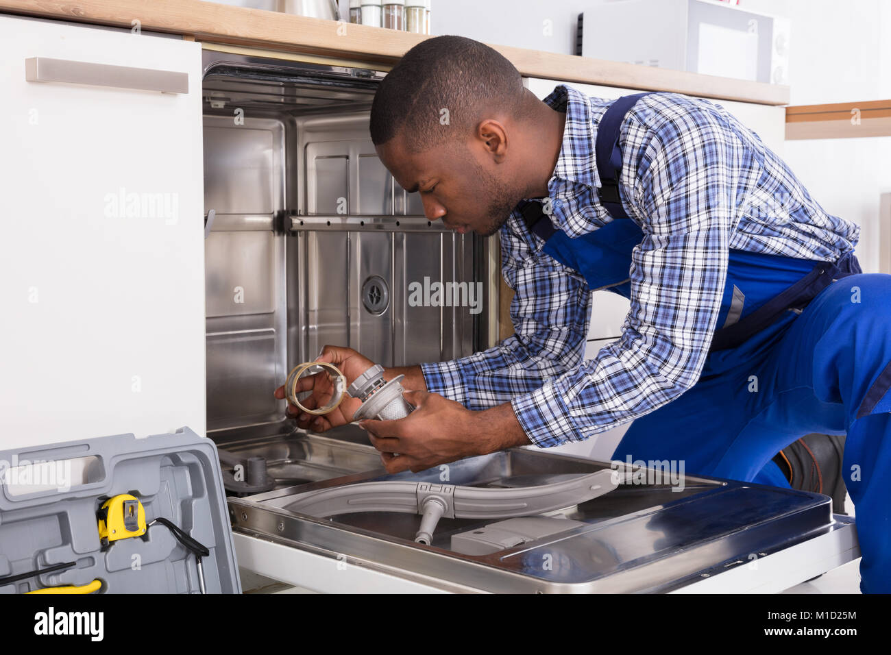 Jeune africaine la réparation réparateur lave-vaisselle dans la cuisine Banque D'Images
