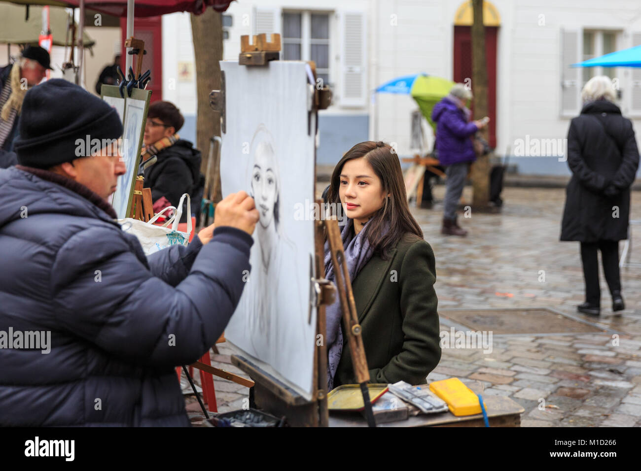 Un peintre croquis une jeune femme sur la Place du Tertre, la célèbre attraction touristique et carré d'artistes à Montmartre, Paris Banque D'Images