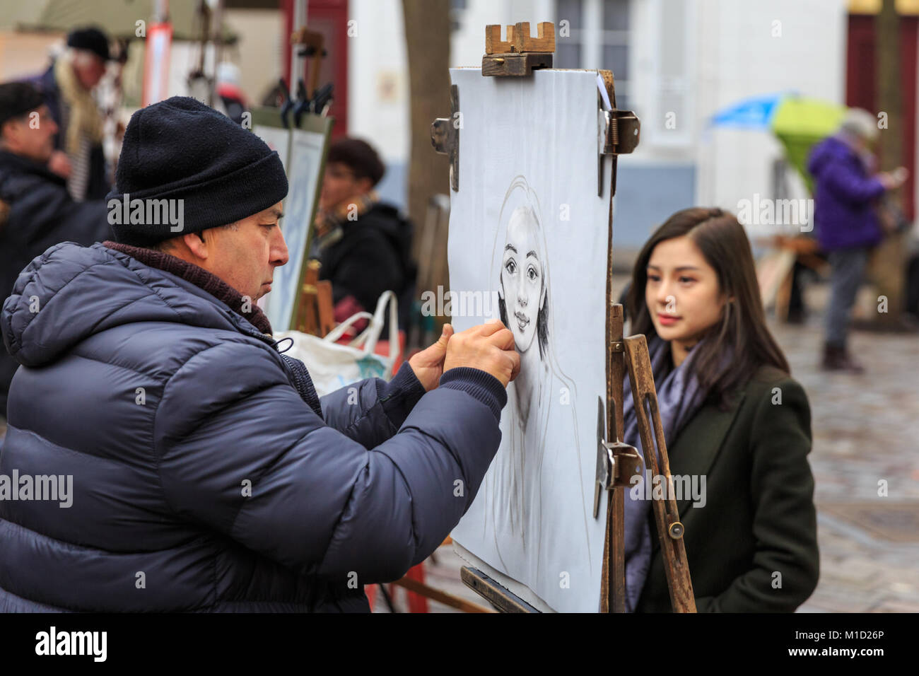 Un peintre croquis une jeune femme sur la Place du Tertre, la célèbre attraction touristique et carré d'artistes à Montmartre, Paris Banque D'Images