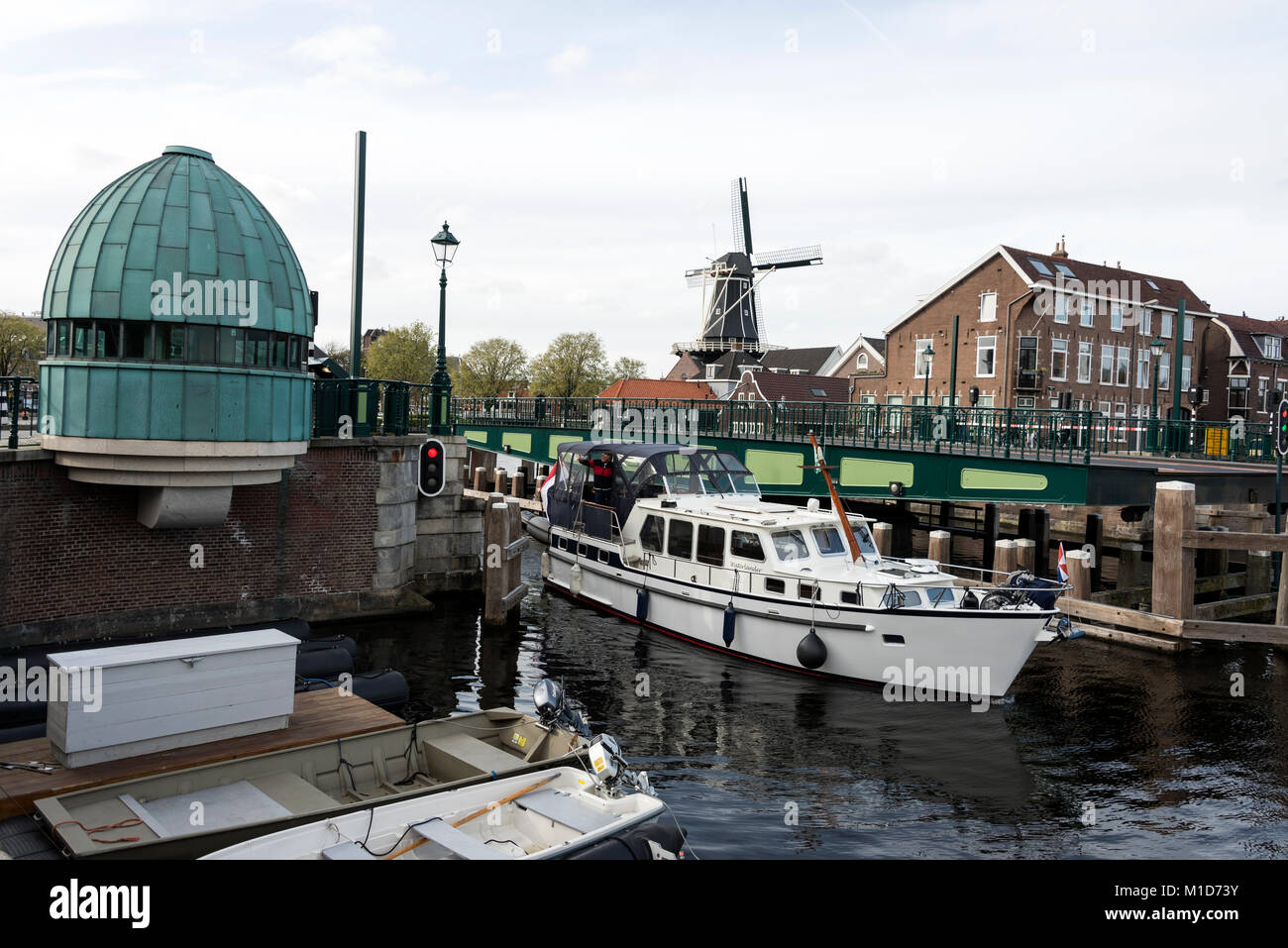 Un pont-levis s'ouvre afin de permettre à un bateau de passer sur la rivière Spaarne Haarlem, en Hollande. Dans la distance est la Molen de Adriaan moulin Banque D'Images