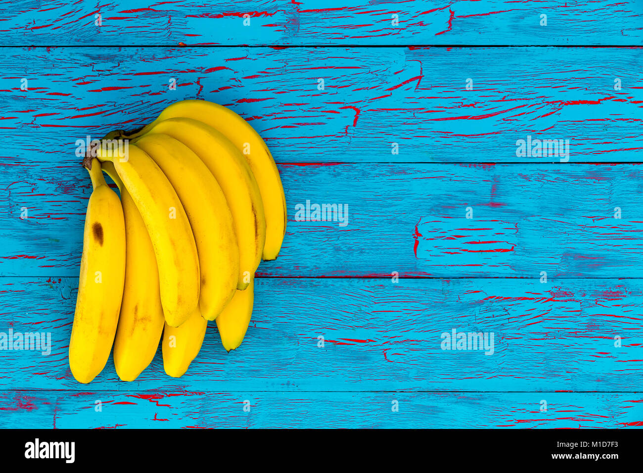 Bande de bananes jaunes mûrs sains sur une peinture crackle exotiques bois bleu turquoise background with copy space Banque D'Images
