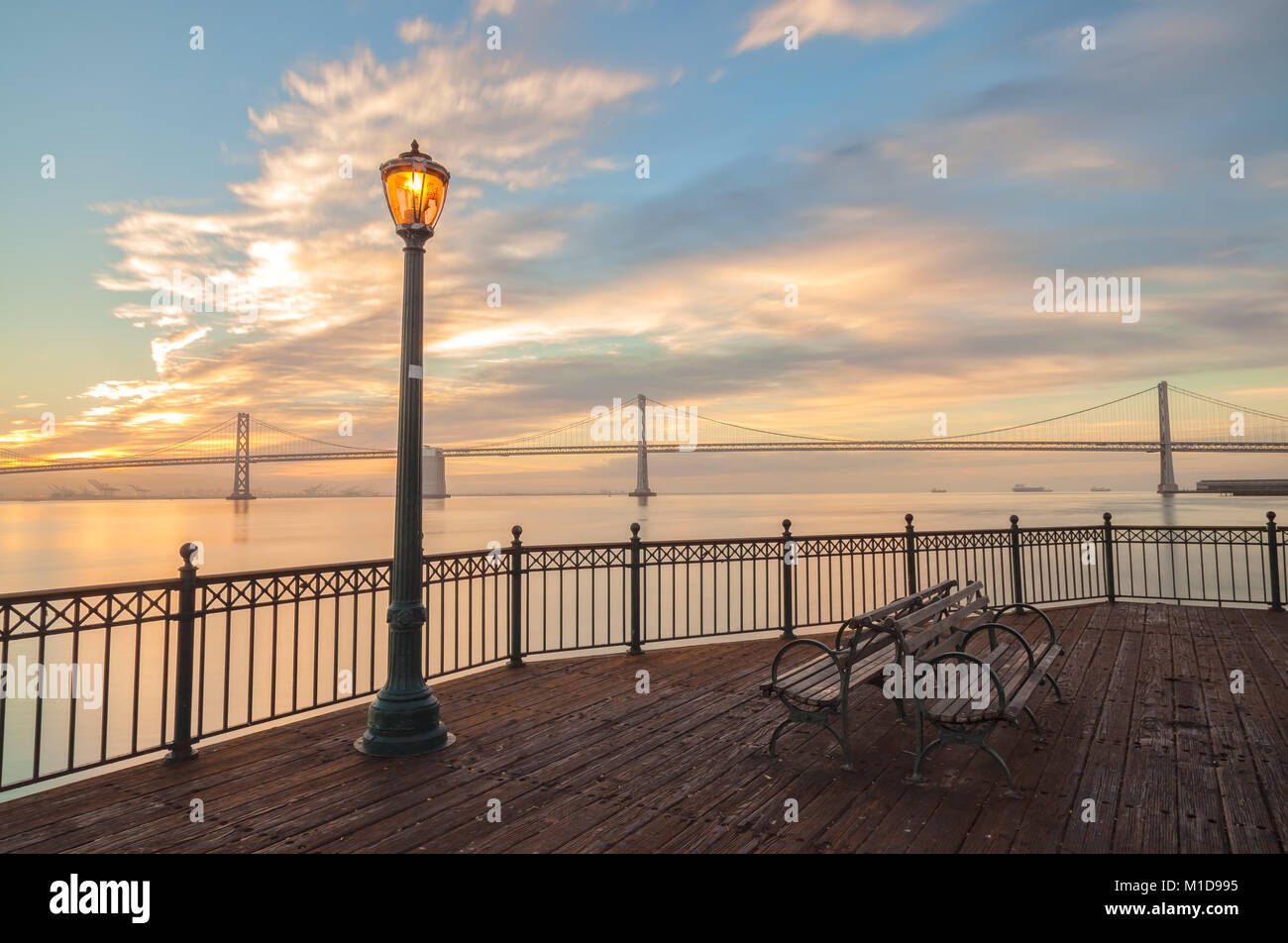 Lampadaire et les bancs au quai 7 au lever du soleil, avec le Bay Bridge dans le fond, San Francisco, Californie. Banque D'Images
