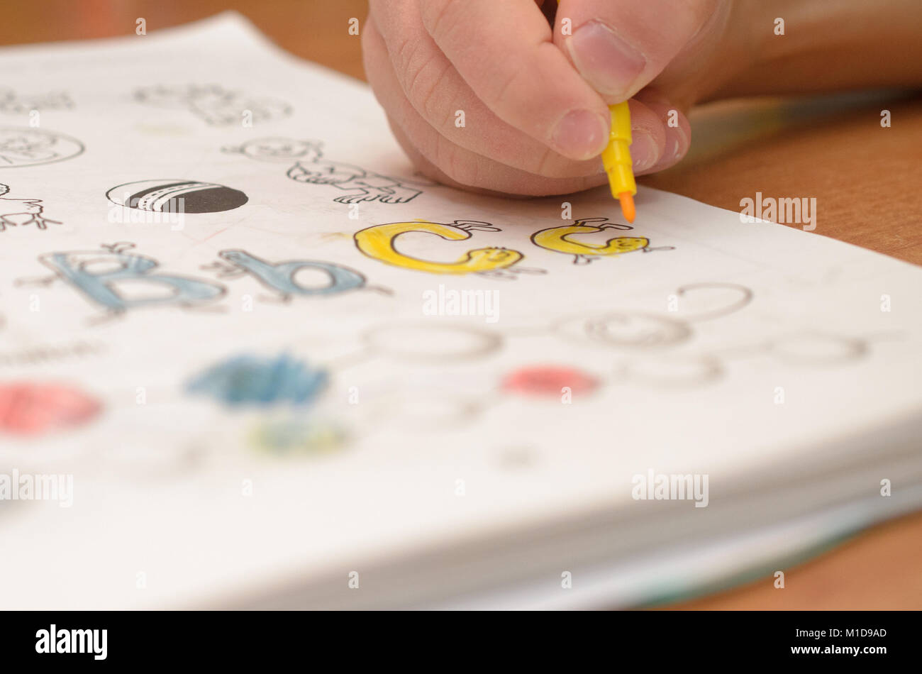 La main d'un enfant écrit et affiche English lettres d'un ordinateur portable et de l'alphabet avec un crayon et un stylo-feutre. Banque D'Images