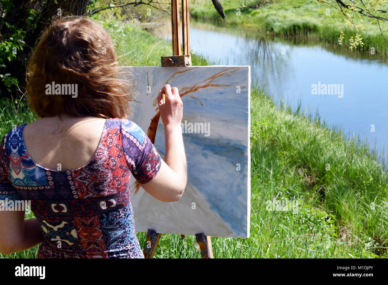 Vue arrière de l'artiste peint un été magnifique paysage avec rivière. Peinture sur toile n'est pas prêt. Banque D'Images